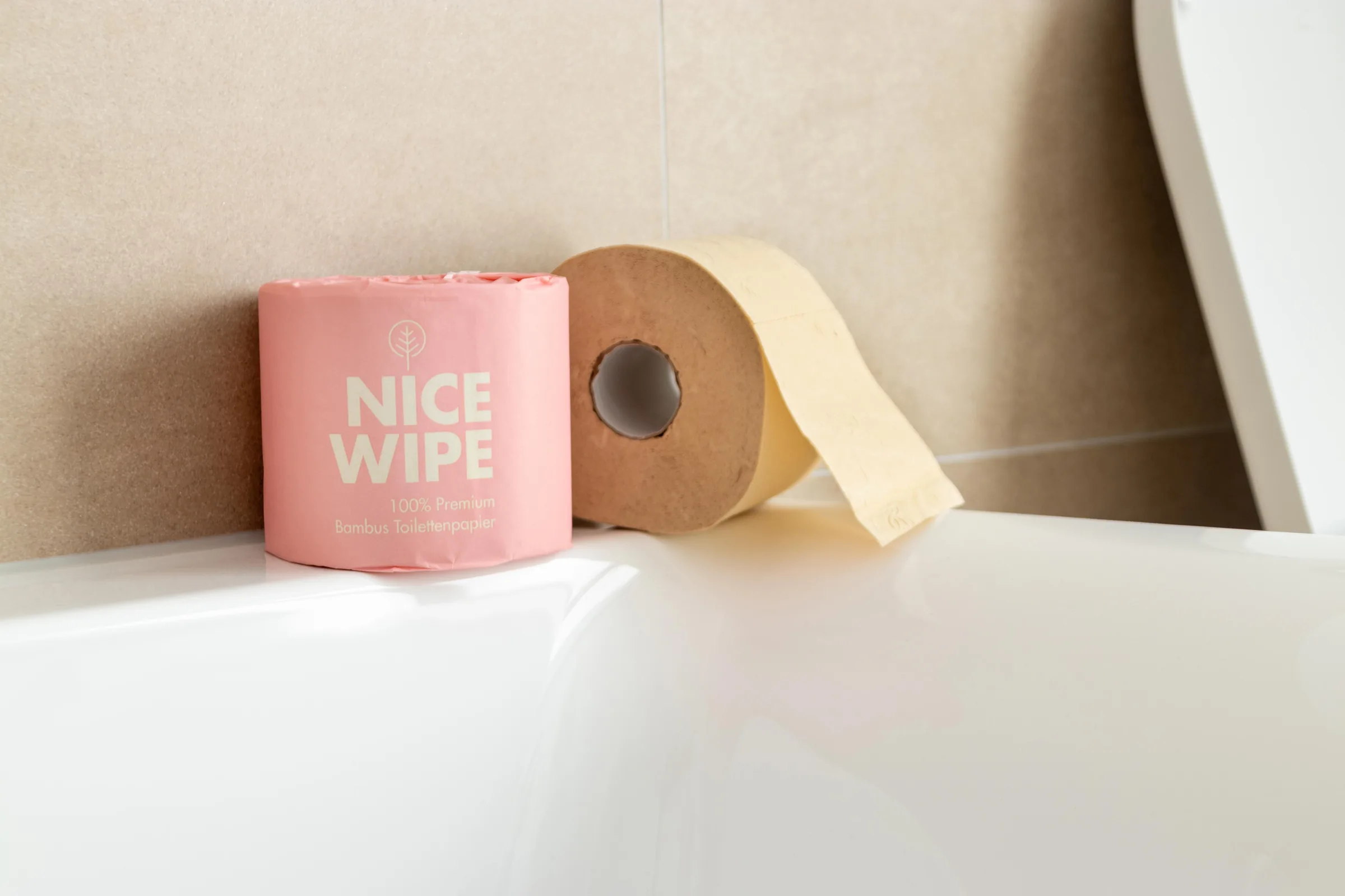 Rolle Bambus-Toilettenpapier in rosa Verpackung auf dem Rand einer Badewanne