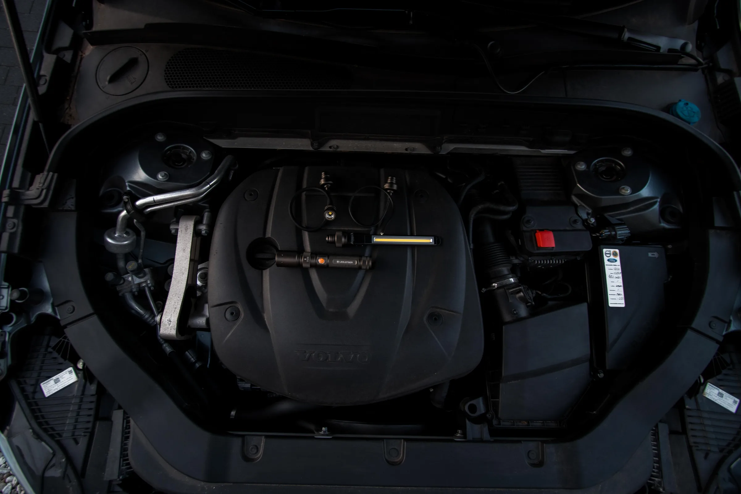 Detailaufnahme eines geöffneten Motorraums mit Motorabdeckung und Anbauteilen