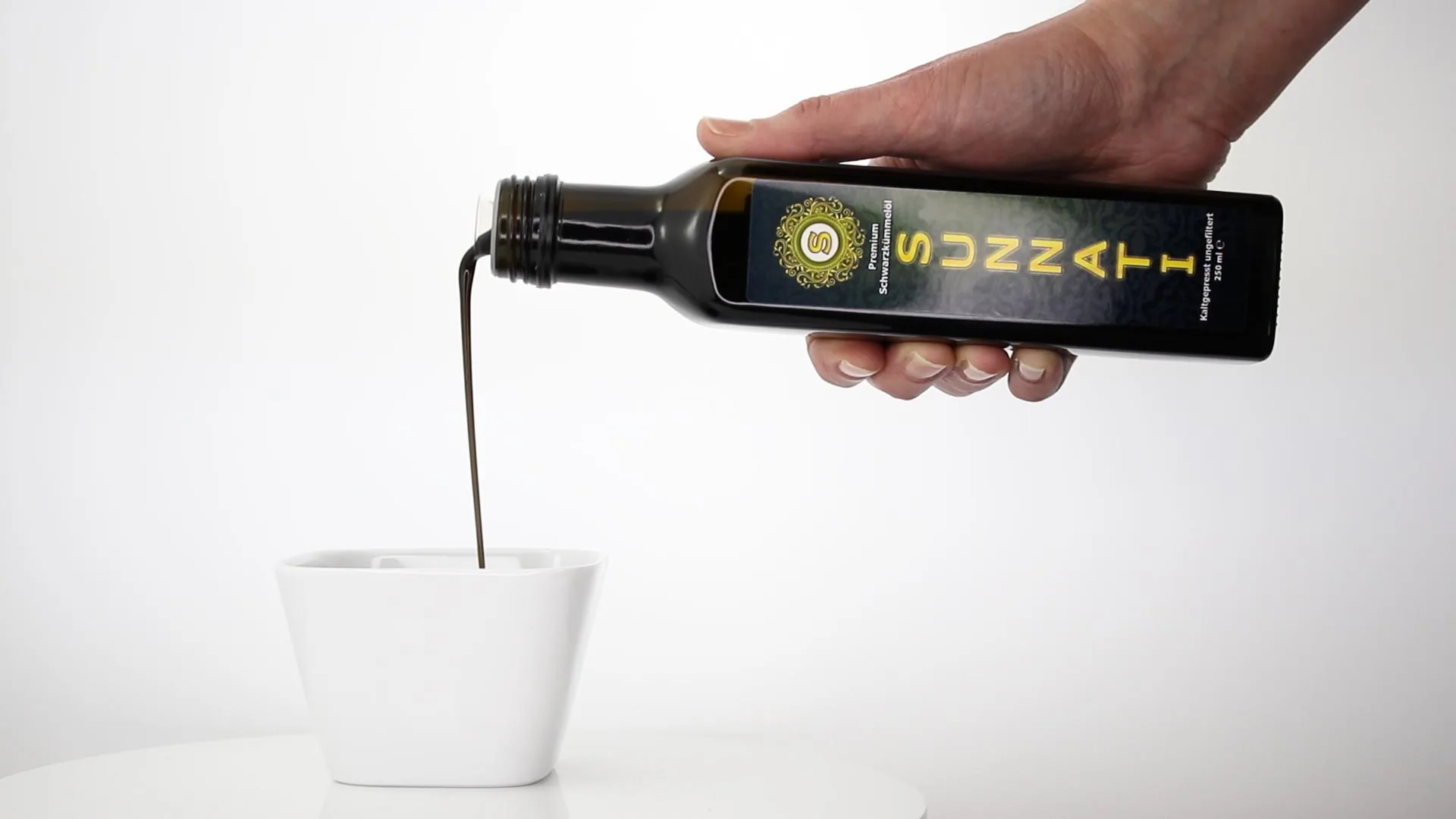 Öl wird aus einer dunklen Flasche in eine weiße Schale gegossen