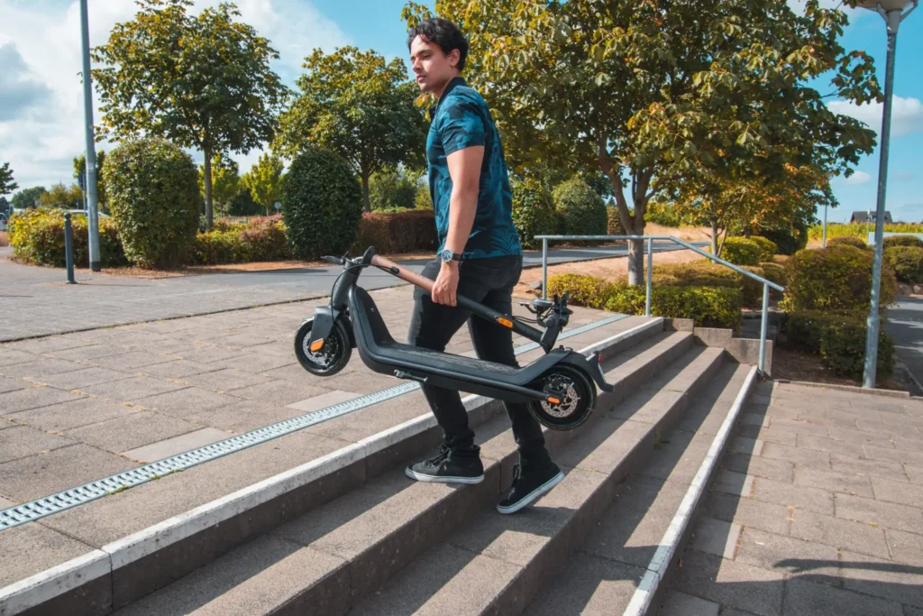 Mann trägt Elektroroller eine Treppe hinauf